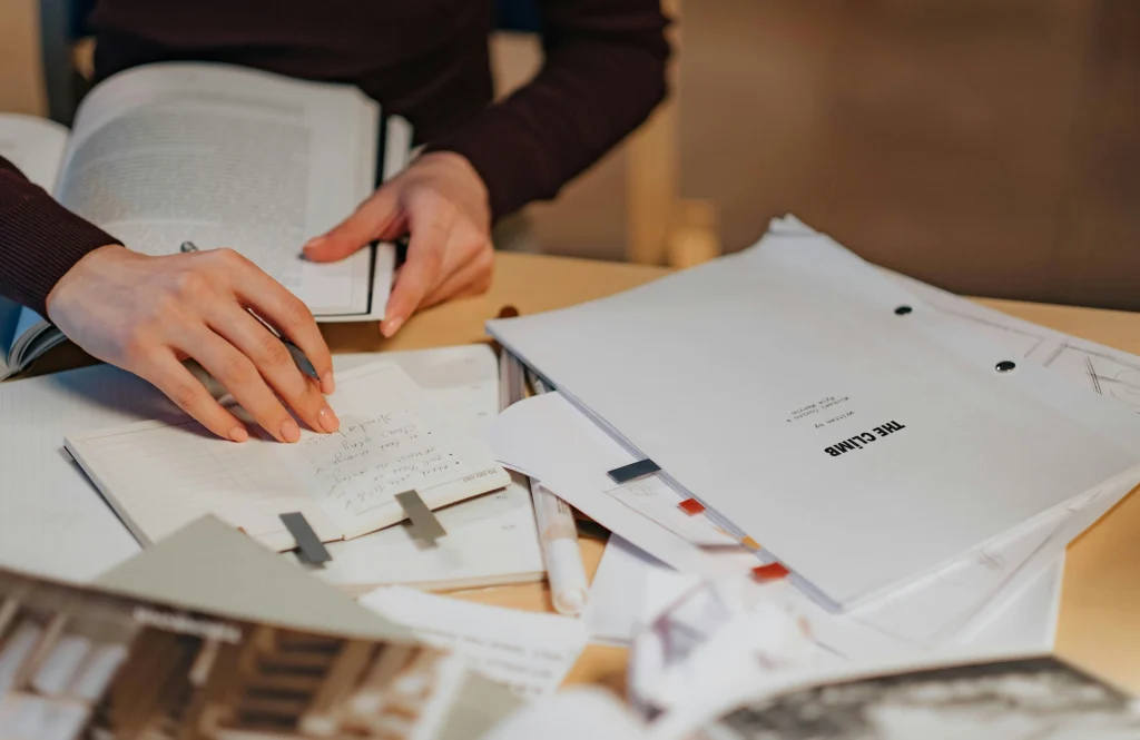 girl trying to do dissertation work with pile of documents